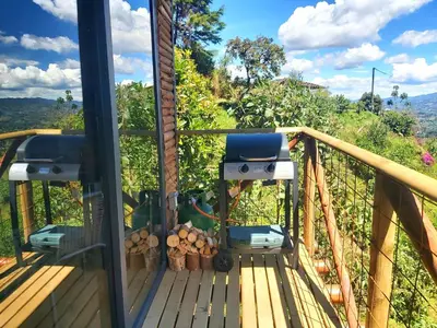 a view from the deck of a house with a grill at Glamping con jacuzzi cerca a Medellin in Guarne