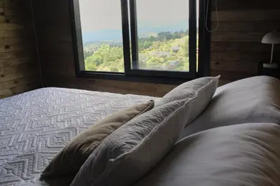 a bed with pillows in a room with windows at Glamping con jacuzzi cerca a Medellin in Guarne