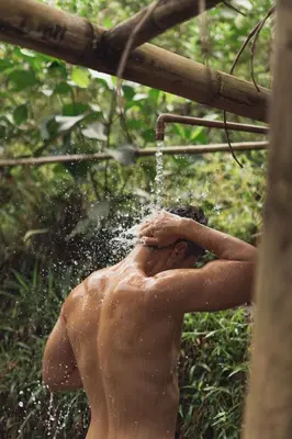 a shirtless man drinking from a water hose at Ecocabaña Pocahontas en rio Santo Domingo, Melcocho in Cocorná