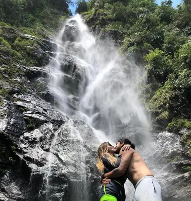 a couple kissing in front of a waterfall at Ecocabaña Pocahontas en rio Santo Domingo, Melcocho in Cocorná
