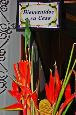 a sign for a store with red flowers and plants at Hospedaje Casa Real in Salamina