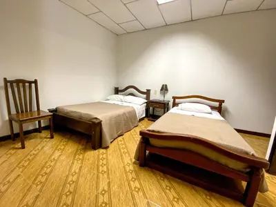 a room with two beds and a chair at Hospedaje Casa Real in Salamina