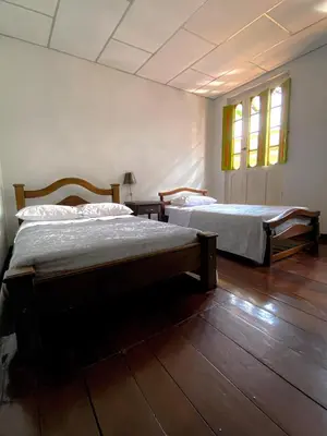 two beds in a room with wooden floors and windows at Hospedaje Casa Real in Salamina