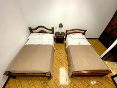 two beds in a small room with wooden floors at Hospedaje Casa Real in Salamina