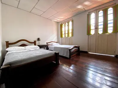 two beds in a room with wooden floors and windows at Hospedaje Casa Real in Salamina