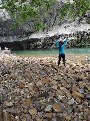 a person standing on a rocky beach with their arms up at Paraíso Escondido Cabañas, Reserva Rio Claro, San Luis-Doradal in San Luis