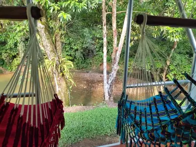 two hanging hammocks with a view of a river at Paraíso Escondido Cabañas, Reserva Rio Claro, San Luis-Doradal in San Luis