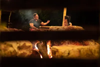 a man and a woman sitting next to a fire at Paraíso Escondido Cabañas, Reserva Rio Claro, San Luis-Doradal in San Luis