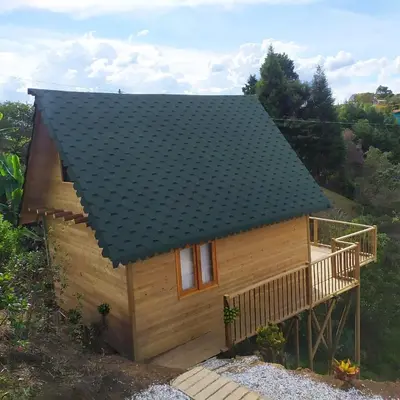 a small wooden house with a black roof at Guané Glamping Ecolodge Jacuzzi Privado Oriente Antioqueño in Guarne