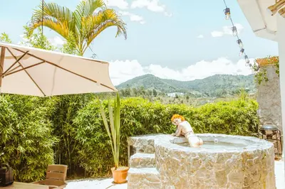 a little girl sitting in a fountain in a yard at Guané Glamping Ecolodge Jacuzzi Privado Oriente Antioqueño in Guarne