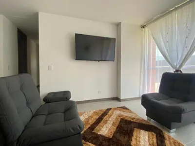 a living room with a couch and a tv on a wall at APTO AMOBLADO 77 mt2 in Itagüí