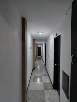a hallway with white walls and a long hallway with doors at Hotel Country Medellin in Medellín