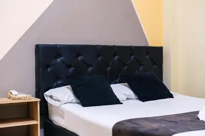 a bed with a black padded headboard and pillows at HOTEL CALLE REAL SUITE in Medellín
