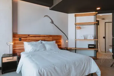 a bedroom with a white bed with a wooden headboard at Hotel 3450 Living Lofts in Medellín
