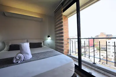 a bedroom with a bed and a large window at Hotel Cabo de la Vela Medellin in Medellín