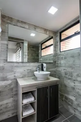 a bathroom with a sink and two mirrors at Hotel Cabo de la Vela Medellin in Medellín