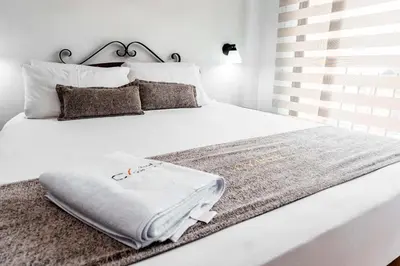 a white bed with a blanket on top of it at Hotel Cabo de la Vela Medellin in Medellín