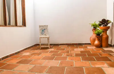 a room with a brick floor with vases and a chair at La Casa de Ana in Jardin
