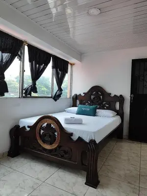 a bedroom with a large wooden bed with a window at Hotel Vegas Sergio in Medellín