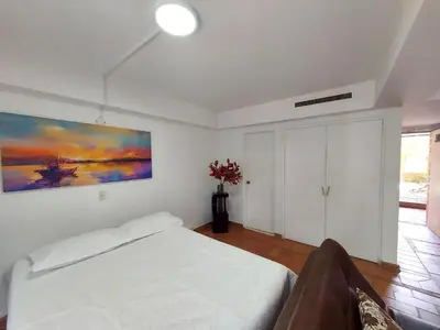 a bedroom with a white bed and a painting on the wall at Apartamentos Tipo Loft Parque del Poblado in Medellín