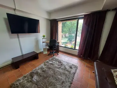 a living room with a couch and a television and a chair at Apartamentos Tipo Loft Parque del Poblado in Medellín