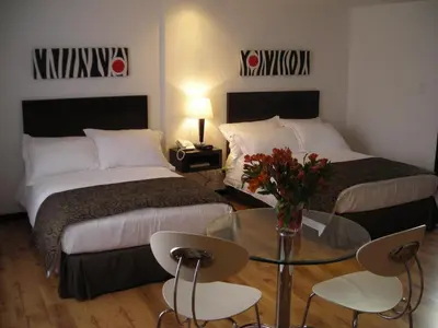a hotel room with two beds and a glass table at Europa Hotel Boutique Manizales in Manizales