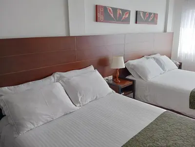 a hotel room with two beds and a table with a lamp at Europa Hotel Boutique Manizales in Manizales