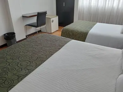 a hotel room with two beds and a chair at Europa Hotel Boutique Manizales in Manizales