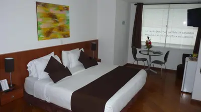 a hotel room with a large bed and a table at Hotel Casa Galvez in Manizales