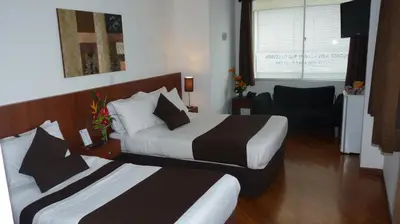 a hotel room with two beds and a chair at Hotel Casa Galvez in Manizales