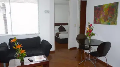 a living room with a couch and a table with flowers at Hotel Casa Galvez in Manizales