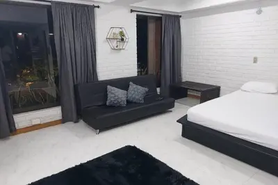 a bedroom with a bed and a couch and a window at Loft Poblado Park in Medellín