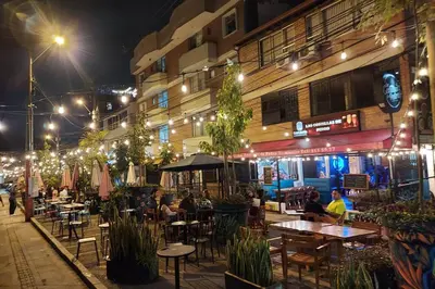 an outdoor restaurant with tables and chairs at night at Loft Poblado Park in Medellín