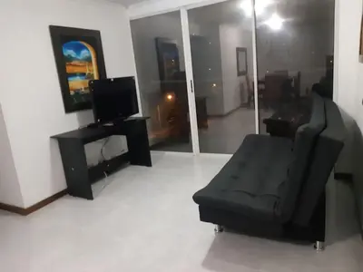 a living room with a black couch and a television at Furnished apartments for rent in Medellín