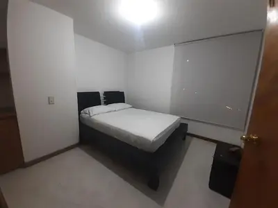a small bedroom with a bed in a white room at Furnished apartments for rent in Medellín