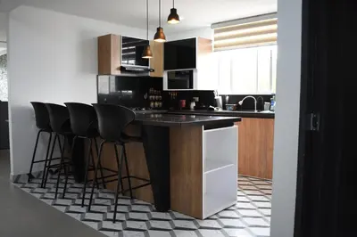 a kitchen with a black counter and black stools at Hostel Boutique Nido de Loros in Medellín