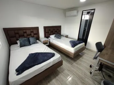 a bedroom with two beds and a desk and a chair at Hostel Boutique Nido de Loros in Medellín