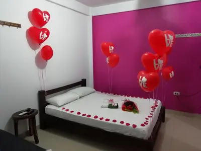 a room with a bed with red heart balloons at La Orquidea in Mariquita