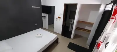 a room with a white bed and a room with a door at La Orquidea in Mariquita