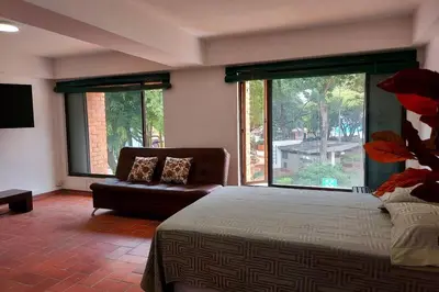 a bedroom with a bed and a couch and a large window at Apartamento en Parque del Poblado in Medellín