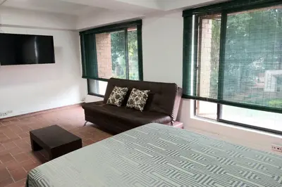 a bedroom with a bed and a chair and windows at Apartamento en Parque del Poblado in Medellín