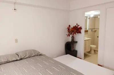 a white bedroom with a bed and a bathroom at Apartamento en Parque del Poblado in Medellín