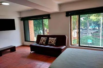a living room with a leather couch and large windows at Apartamento en Parque del Poblado in Medellín