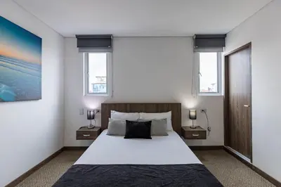 a bedroom with a large bed and two windows at Hotel Velero in San Antonio de Pereira