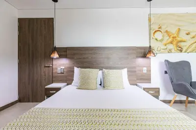 a bedroom with a large white bed and a chair at Hotel Velero in San Antonio de Pereira
