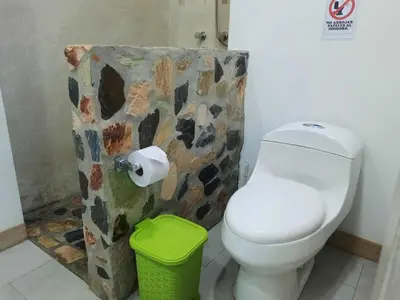 a bathroom with a toilet and a green trash can at Casa De Campo in Santuario