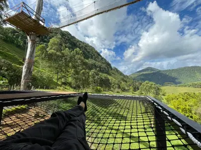 a person laying on a bridge looking out at the mountains at Gulupa Ecolodge in Jardin
