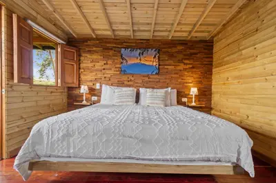 a bedroom with a large bed in a wooden wall at Gulupa Ecolodge in Jardin