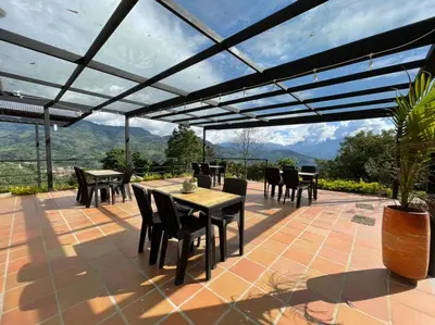 a patio with tables and chairs and a view of mountains at Gulupa Ecolodge in Jardin