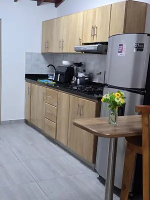 a kitchen with wooden cabinets and a refrigerator and a table at Apartamento Guatapé Plaza in Guatapé